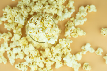 Popcorn in a glass bowl on yellow background