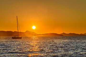 Naklejka na ściany i meble Boat sailing at sunset