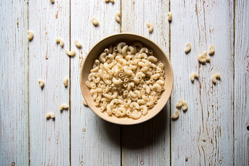 Top view of macaroni pasta in a bowl on a background.