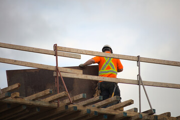 construction worker holding plywood on roof wood beams