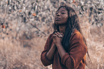 Afro Girl closed her eyes, praying. Hands folded in prayer concept for faith, spirituality and religion