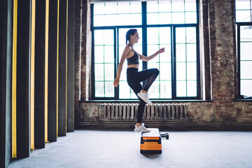 Slim woman practicing step exercise in gym
