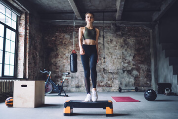 Fototapeta na wymiar Slim female athlete training on step platform
