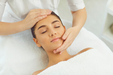 Fototapeta na wymiar Close-up of serene woman getting procedure of relaxing manual facial massage from masseur