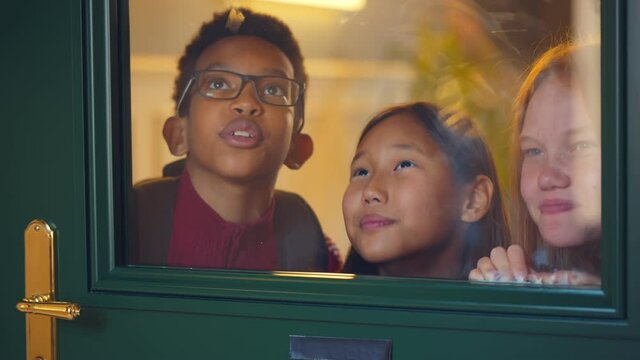 Happy diverse classmates peeking through glass door waiting for end of classes