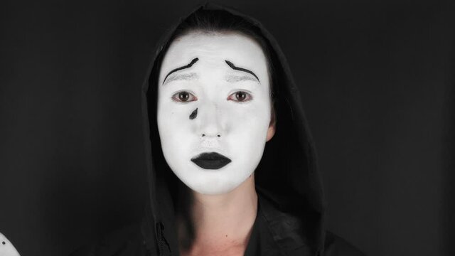Portrait of a mime and bodypainting woman in white with black lips. Mime woman on black background. 