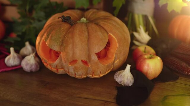 Scary Halloween style carved pumpkin. Jack O Lantern decoration illuminating with burning candle inside. Creepy Jack-o'-Lantern face. 4K footage.