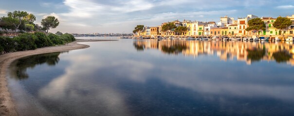 Fototapeta premium Panorama of Portocolom harbour with boats, traditional houses and calm sea with reflection, Mallorca, Spain.