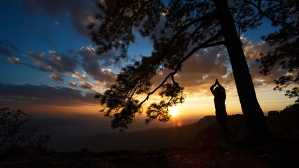 Silhouette image of trees and people at sunrise, Phu Kradueng, Thailand