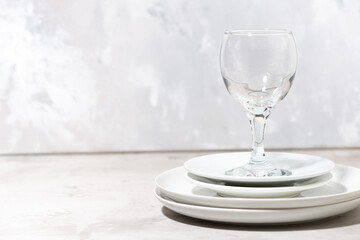 stack of clean white plates and a wine glass. serving element