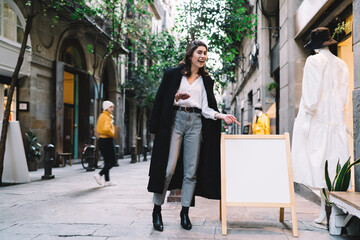 Fototapeta premium Stylish woman pointing to banner ad on street