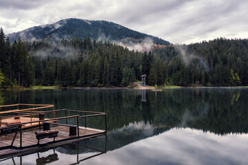 Amazing view of the alpine lake Synevyr (sea eye of Carpathians) in Carpathian mountains with reflection in the clear water, favorite tourist destination, misty spring landscape, Zakarpattia, Ukraine