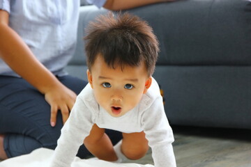 Fototapeta premium close up Asian baby crawling on the floor with mother watching over background