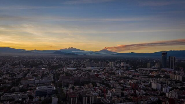 Epic hyperlapse sunrise with 2 volcanoes as foreground, one which is active with smoke.
