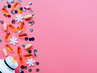 Pills, confetti, Christmas toys on a pink background, flatly, copyspace fall out of the jar. Medical banner concept for new year or Christmas. Ideas for Christmas medical promotions