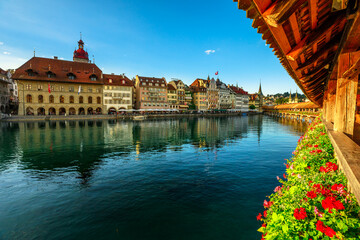 Old city center of Lucerne on Lake Lucerne, Switzerland. Kornschutte or town hall from historic covered wooden Chapel Bridge with Water Tower and flowering geraniums reflecting on Reuss river.