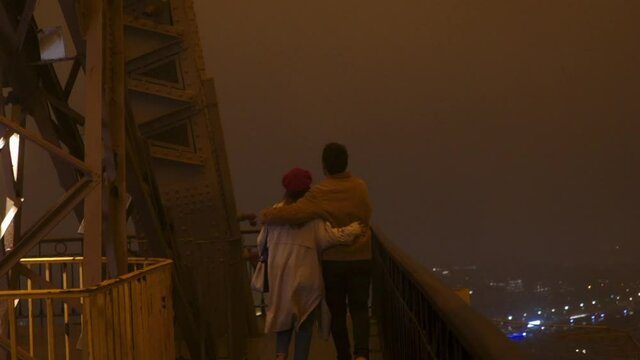 Loving couple observing night city from tower
