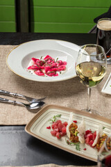 Beetroot ravioli stuffed with white sauce and glass of white wine on the table at restaurant