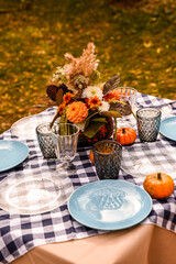 Autumn bouquet of beautiful flowers and pumpkin on table. Concept of autumn festive decoration for Thanksgiving day or Halloween. We can see on the table blue and transparent crockery.