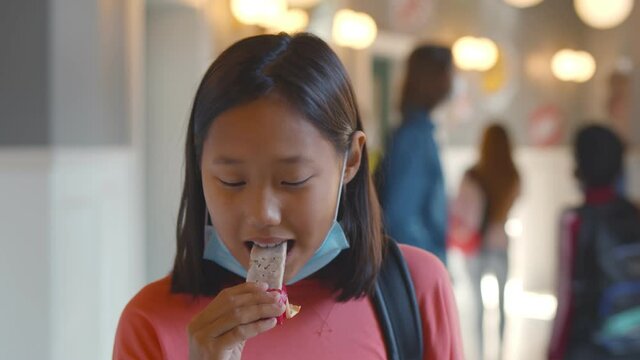 Portrait of asian schoolgirl putting off facial mask and eating snack