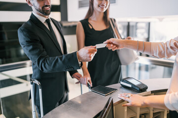 Business people makes card payment at check-in at reception.
