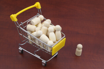 Shopping cart with many wooden figures of people, one person standing outside. Boss or HR hire...