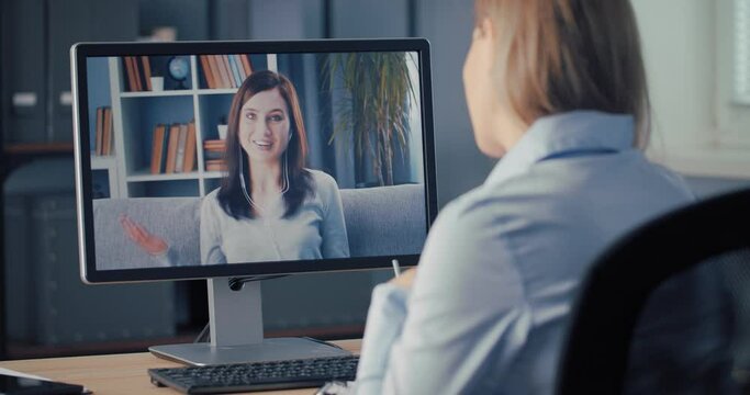 Back view of female employee having interview with young happy woman through video call on computer. Distance conversation. Technology concept.