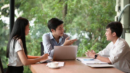 Businessman explaining new business ideas to peers in meeting room.