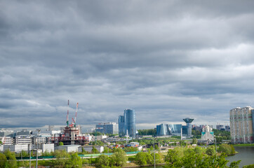 New buildings against the backdrop of a dramatic sky. greenery and water with a running motorway