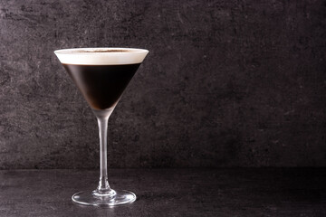 Martini espresso cocktail in glass on black background. Copy space