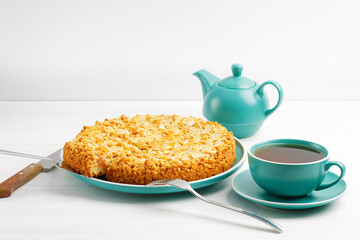 Apple pie with almond petals and cup of tea on white wooden table. Copyspace.
