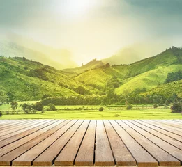 Fotobehang Geel houten tafelblad met de achtergrond van het berglandschap