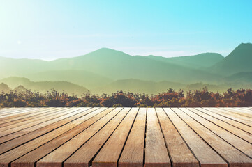 empty wooden table top with the mountain landscape against sunset sky