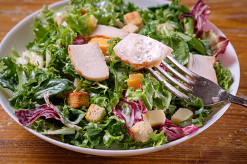 Plate of traditional Caesar salad with chicken and cheese