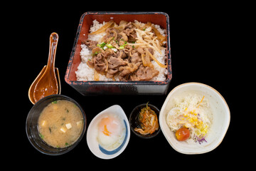 Rice Topped with sliced beef and Soft-boiled egg and salad and  kimchi and miso soup set  of Japanese food on black background 