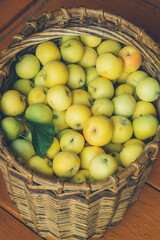 green apples in a knitted basket on a wooden background