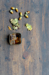 Fall. Autumn mood. Image of whiskey and oak leaves and acorns on a wooden table.