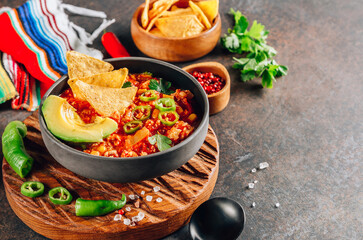 Chili Con Carne in bowl with tortilla chips on dark background. Mexican cuisine. Selective focus. With copy space
