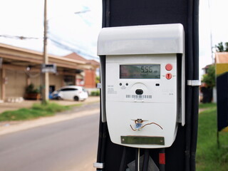 Digital electricity meter on the pole. A new high-precision electric current technology On the background of paved roads and houses. Selective focus
