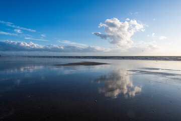 eine große weiße Wolke spiegelt sich im Meer