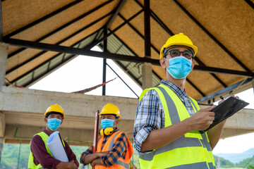 Group of engineering team wearing protective face masks for safety meeting at building site.