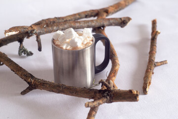 Fototapeta premium A cup of hot chocolate with marshmallows. On a light background with branches