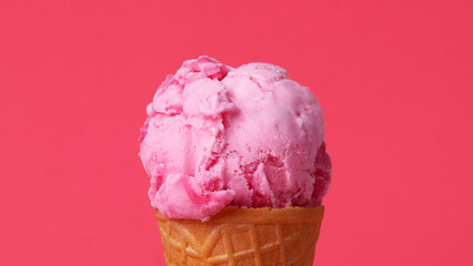 Strawberry Ice cream scoop in waffle cone on pink background.
