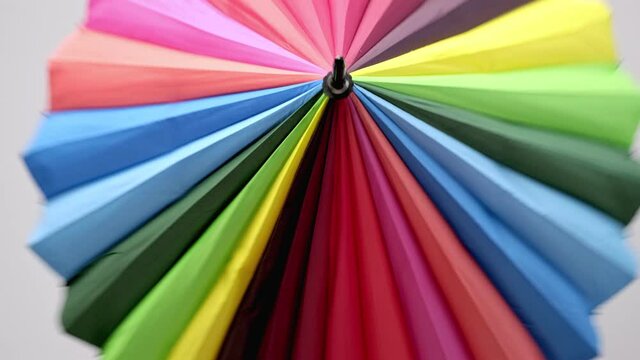 Beautiful young girl with dyed hair and a short haircut. Opens a bright colored umbrella and twists it in front of the camera.