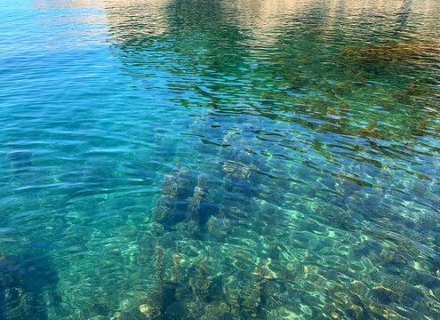 Turquoise crystal clear water in the Mediterranean sea. Scenic algae on the pebble seabed. Beautiful seascape.