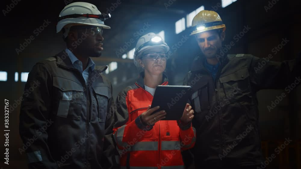 Leinwandbilder three diverse multicultural heavy industry engineers and workers in uniform stand in dark steel fact