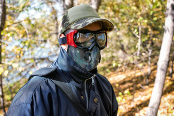 A man wearing a respirator mask and protective glasses in the forest at COVID-19 period.