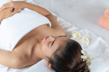 Fototapeta na wymiar Beautiful Asian woman lying down on massage bed relaxing in spa salon