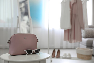 Stylish woman's bag and sunglasses on table in room. Space for text