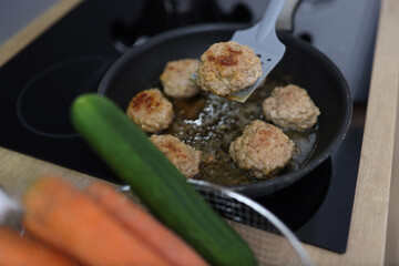 Chef uses spatula to flip over fried cutlets in kitchen closeup. Cooking meat dishes concept.